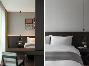 A modern bedroom featuring a luxury white bed with dark wood accents and a minimalist design.