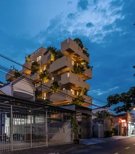 Modern house featuring a concrete exterior with green roofs, set against a blue sky with clouds.