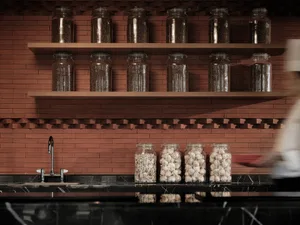 Modern kitchen featuring glass jars with food items on shelves and garlic on the countertop.