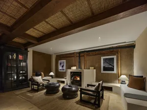 A modern living room with concrete walls and floor, featuring furniture and decor. The space is well-lit with natural light a
