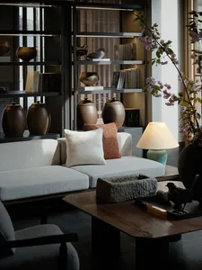 A modern living room with a white textured sofa adorned with pillows, a wooden coffee table with decorative objects, and a la