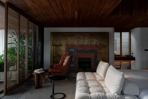 Modern living room with white couch, wooden ceiling, and fireplace.