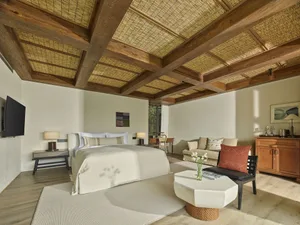 A minimalist residential room featuring a bed, sofa, and side table with wood elements.