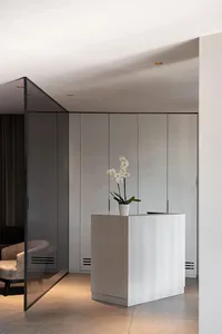 A minimalist office reception area with a white concrete desk and a white orchid plant.