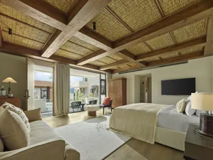 Modern residential bedroom featuring natural wood and fibers, with a comfortable bed, a cozy sofa, and a well-designed space.
