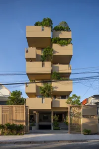 一棟現代住宅建築採用砂岩外牆，設有高架植栽槽與陽台。