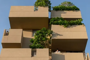 Modern residential building with concrete balconies and green plants.