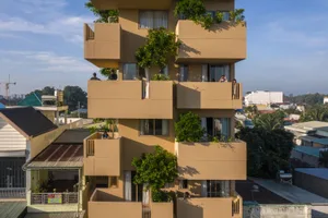 一棟現代住宅建築，擁有混凝土露台與植栽。