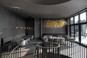 Modern restaurant interior with black and glass seating area and circular black railings.