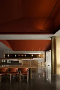 A modern restaurant interior with a terracotta ceiling and a gold pillar, showcasing contemporary design elements.