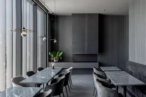 A modern restaurant with sleek marble tables and chairs, featuring industrial-style lighting and minimalist design.