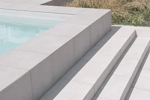 Concrete stairs leading into a modern swimming pool.
