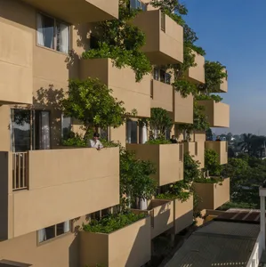 Modern apartment building with concrete balconies adorned with lush greenery and plants.