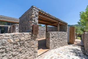 一座以石材建造的住宅結構，搭配木質挑簷與木門。