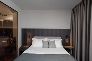 Minimalist bedroom featuring a gray fabric bed with white bedding and a dark gray wooden headboard.