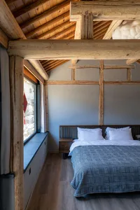 Modern barn-style bedroom featuring a wooden bed frame and rustic wooden beams on the ceiling.