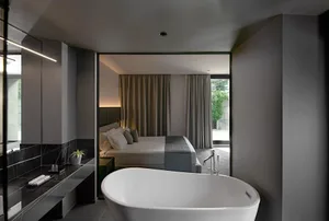 A modern bathroom bedroom suite featuring a concrete countertop and light gray curtains.