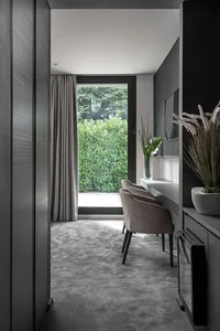 A modern dining room featuring grey tiles and concrete elements, with a large window providing natural light.