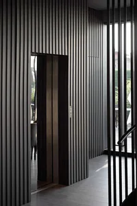 A modern elevator interior with metallic panels and a glass door.