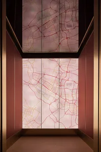 A modern lobby interior featuring a glass wall displaying a map with red and yellow lines and patterns.