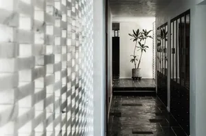 A modern minimalist corridor with tile and glass flooring, and a tall potted plant in the distance.