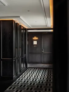 A hotel suite corridor with dark wood paneling and a geometric patterned floor.