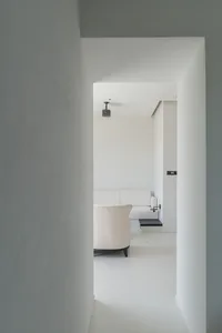 A minimalist living room with white walls, furniture, and flooring.