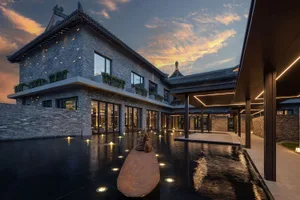 Modern building exterior featuring brick and concrete materials with lighting accents and a water feature.