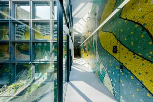 Modern corridor interior featuring vibrant tiled walls and glass panels.