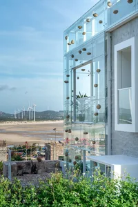 Modern building with glass walls overlooking blue water.