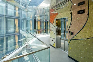 Modern hotel interior with glass walls and a colorful mosaic wall.