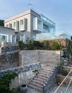 A modern residential exterior featuring stone walls and glass balconies.