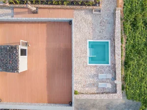 Aerial view of a modern residential patio featuring composite wood flooring and a small, square-shaped swimming pool.