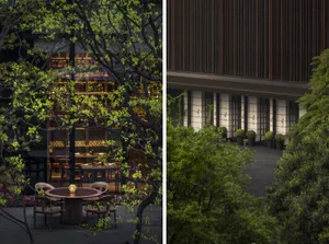 Modern outdoor seating area with wooden tables and chairs surrounded by greenery at dusk.