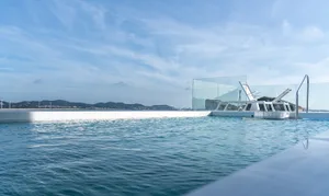 Modern glass pool with a view of the water and mountains in the distance.