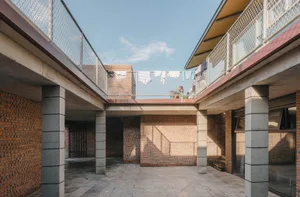 An image of a residential patio made of red brick and concrete, with laundry hanging on a clothesline in the background.