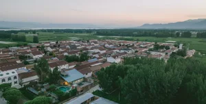 Aerial view of a village surrounded by green fields and distant mountains.