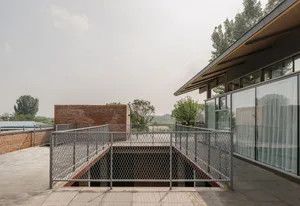 A modern metal roof deck with a brick building in the background and a flat roof with a clear sky.