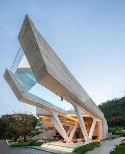 A modern building with a concrete and glass exterior, featuring an angular, open design.