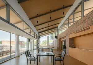 Modern patio kitchen featuring glass walls, brick accents, and wooden flooring.