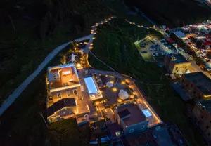 現代住宅建築在夜間燈光照亮，搭配泳池與戶外休憩區。