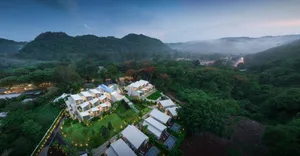 Aerial view of a modern residential property nestled in a lush, green landscape with mountains in the background.