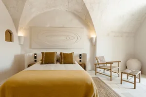 A minimalist bedroom with a yellow bedspread and wooden furniture.