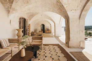 A spacious, modern minimalist living room with concrete, wood, and jute textures.