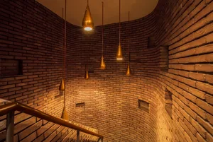 A modern industrial staircase with brick walls and hanging lights.