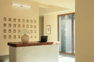 A minimalist office with a concrete front desk featuring a laptop and table lamp.