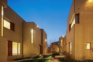 A modern residential exterior with clay brick walls and illuminated windows.