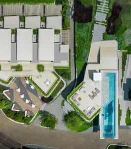 A modern architectural design featuring a rooftop swimming pool, outdoor seating areas, and greenery.