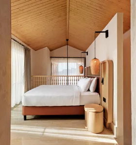 Modern bedroom with brown furniture, white sheets, and rattan pendant lights.