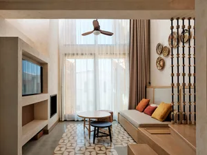 Modern living room with concrete flooring, wooden furniture, and glass fireplace.